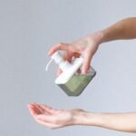 Close-up of a person applying liquid soap for hand hygiene. Indoors, bright lighting.